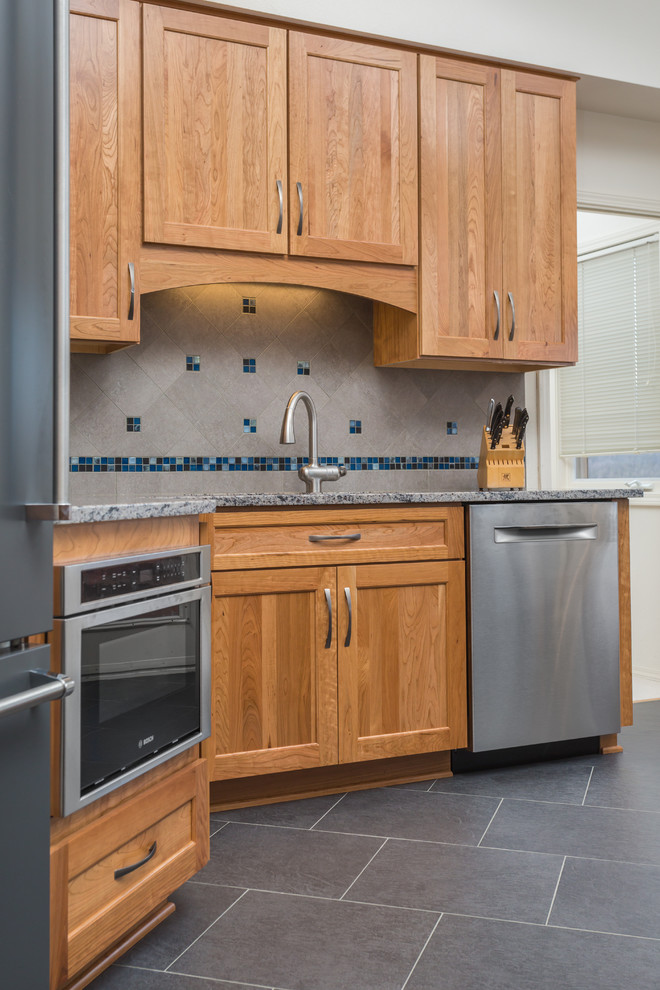 Example of a mid-sized transitional l-shaped porcelain tile open concept kitchen design with an undermount sink, shaker cabinets, medium tone wood cabinets, quartz countertops, gray backsplash, porcelain backsplash, stainless steel appliances and an island