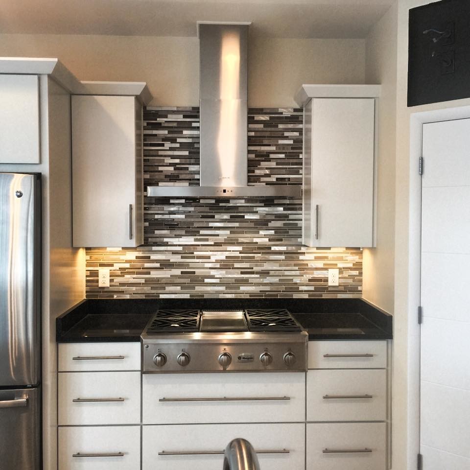 Inspiration for a mid-sized kitchen remodel with white cabinets, solid surface countertops, gray backsplash, stone tile backsplash and stainless steel appliances