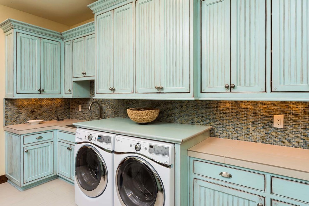 Design ideas for a large country galley dedicated laundry room in Other with an undermount sink, blue cabinets, beige walls, a side-by-side washer and dryer, beaded inset cabinets, tile benchtops and ceramic floors.