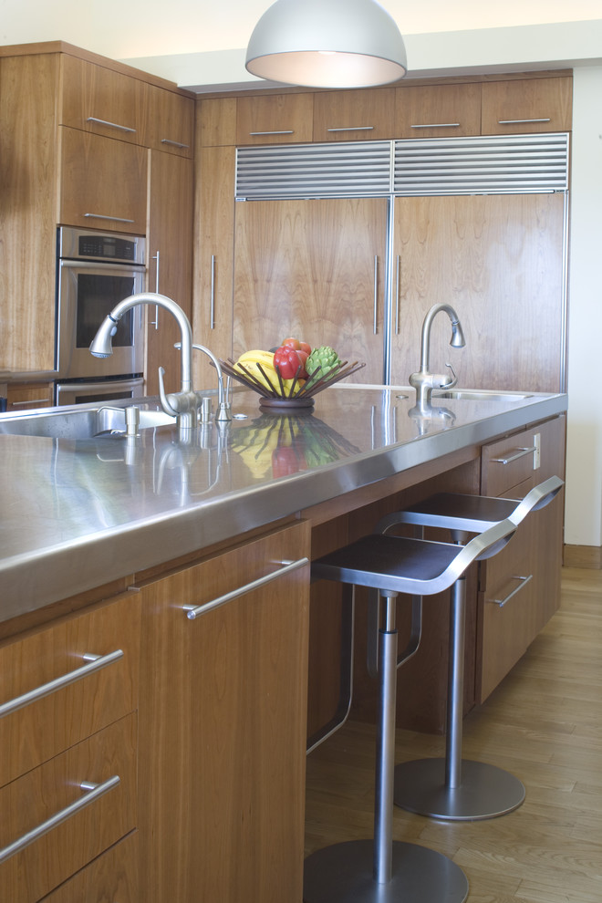 This is an example of a contemporary kitchen in Los Angeles with panelled appliances, an integrated sink, stainless steel benchtops, flat-panel cabinets and medium wood cabinets.