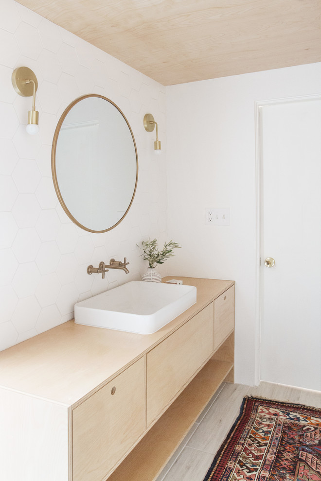 Mid-sized scandinavian master bathroom in Los Angeles with flat-panel cabinets, light wood cabinets, an undermount tub, a shower/bathtub combo, a one-piece toilet, white tile, ceramic tile, white walls, a vessel sink, wood benchtops, beige floor, an open shower and beige benchtops.