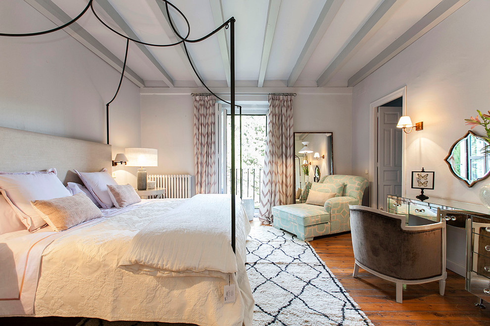 This is an example of a large eclectic master bedroom in Madrid with white walls, dark hardwood floors and no fireplace.