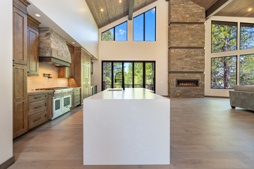Large transitional single-wall laminate floor and brown floor open concept kitchen photo in Phoenix with an undermount sink, recessed-panel cabinets, brown cabinets, quartz countertops, white backsplash, stainless steel appliances, an island and white countertops