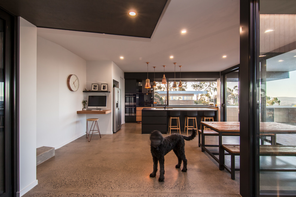 Large contemporary galley eat-in kitchen in Hobart with a double-bowl sink, flat-panel cabinets, grey cabinets, laminate benchtops, glass sheet splashback, black appliances, concrete floors and with island.