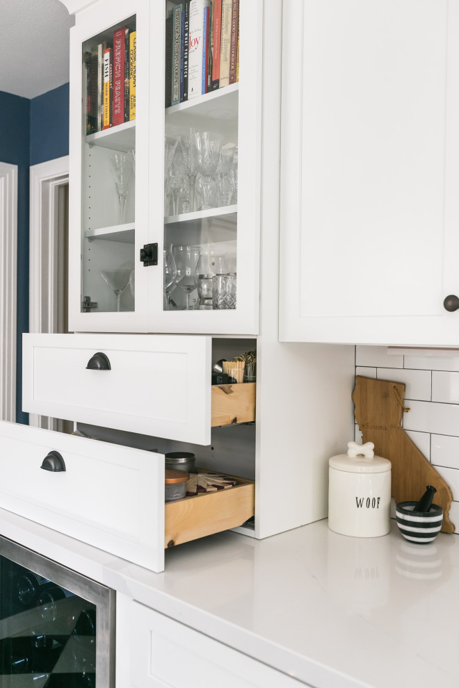 Inspiration for a mid-sized eclectic galley eat-in kitchen in San Francisco with a farmhouse sink, shaker cabinets, white cabinets, quartz benchtops, white splashback, ceramic splashback, coloured appliances, vinyl floors, no island, black floor and white benchtop.