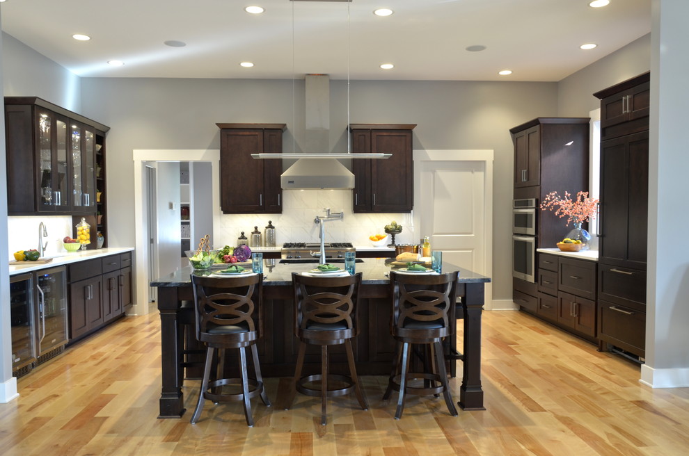 Open concept kitchen - large transitional u-shaped light wood floor open concept kitchen idea with an undermount sink, shaker cabinets, dark wood cabinets, quartz countertops, white backsplash, stainless steel appliances, an island and stone tile backsplash
