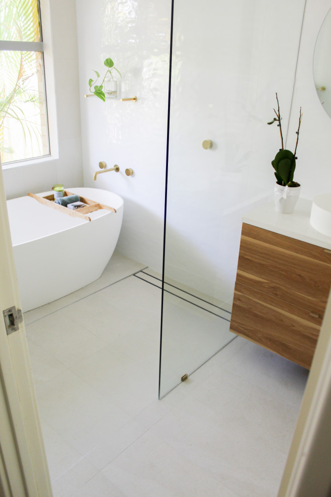 This is an example of a medium sized modern bathroom in Perth with flat-panel cabinets, dark wood cabinets, a freestanding bath, white tiles, porcelain tiles, white walls, porcelain flooring, a vessel sink, engineered stone worktops, grey floors, an open shower, white worktops, a single sink and a floating vanity unit.