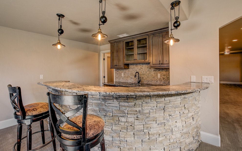 Inspiration for a mid-sized country u-shaped seated home bar in Denver with an undermount sink, raised-panel cabinets, medium wood cabinets, granite benchtops, beige splashback, stone slab splashback and porcelain floors.
