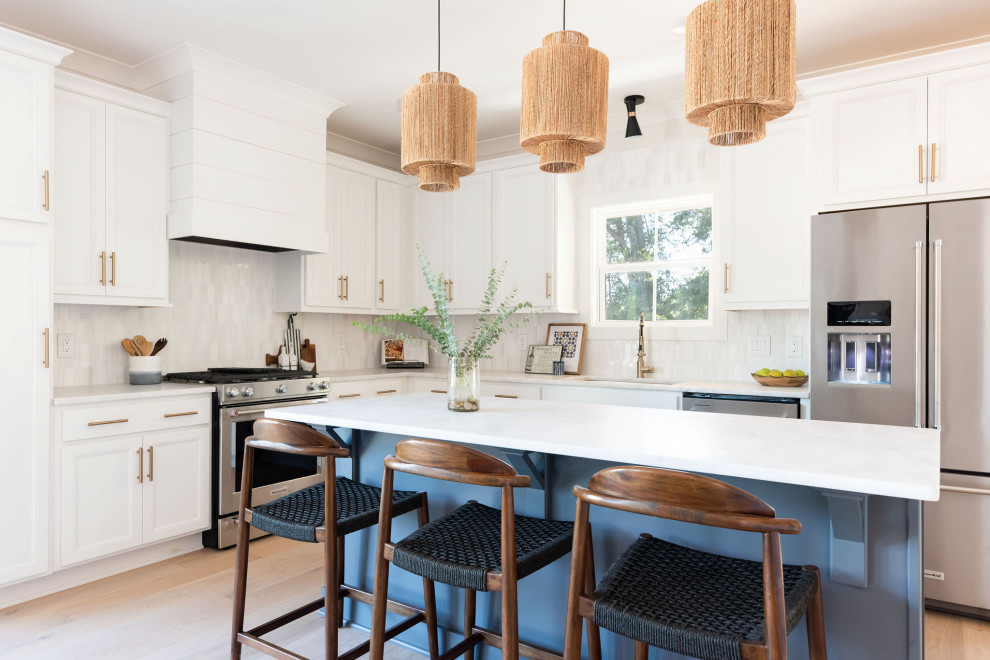 Inspiration for a transitional u-shaped medium tone wood floor and beige floor kitchen remodel in Nashville with an undermount sink, recessed-panel cabinets, white cabinets, quartz countertops, white backsplash, stainless steel appliances, an island and white countertops