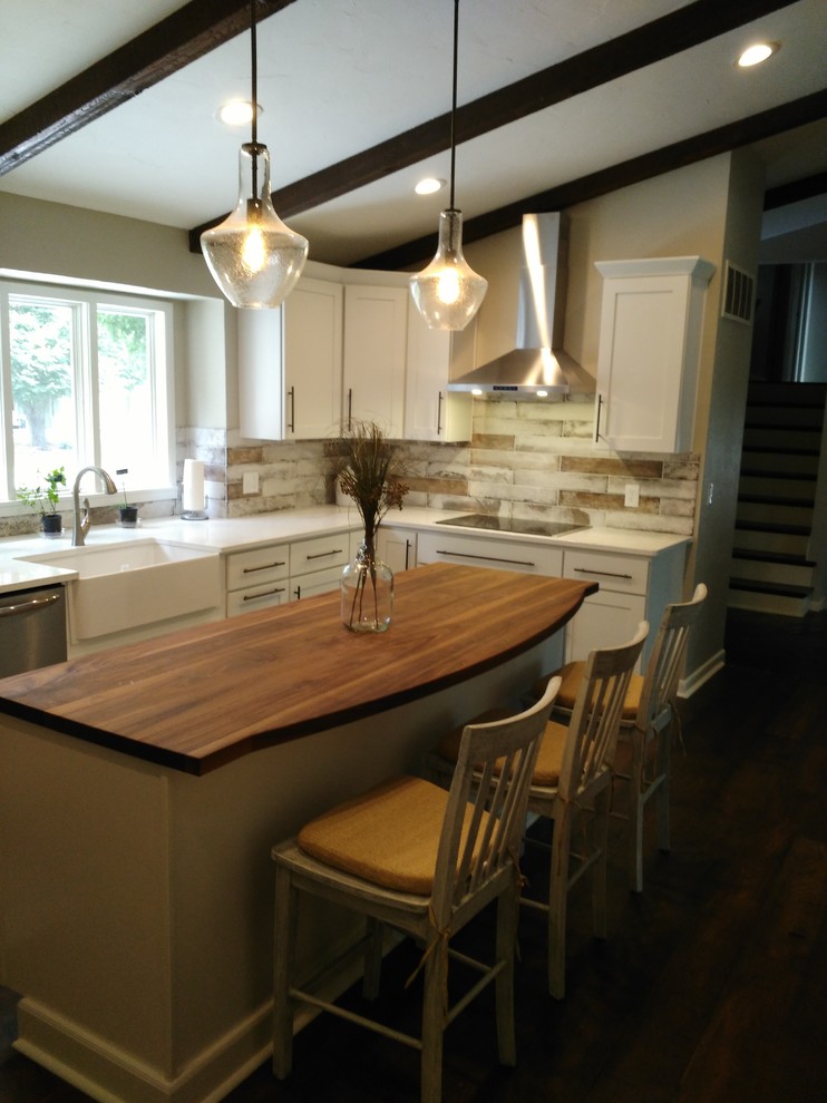 Example of a mid-sized transitional l-shaped dark wood floor and brown floor eat-in kitchen design with a farmhouse sink, shaker cabinets, white cabinets, wood countertops, gray backsplash, marble backsplash, stainless steel appliances and an island