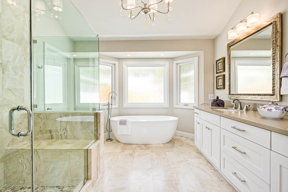 Expansive transitional master bathroom in Los Angeles with shaker cabinets, white cabinets, a freestanding tub, an alcove shower, a one-piece toilet, beige walls, marble floors, a drop-in sink, engineered quartz benchtops, beige floor and a hinged shower door.