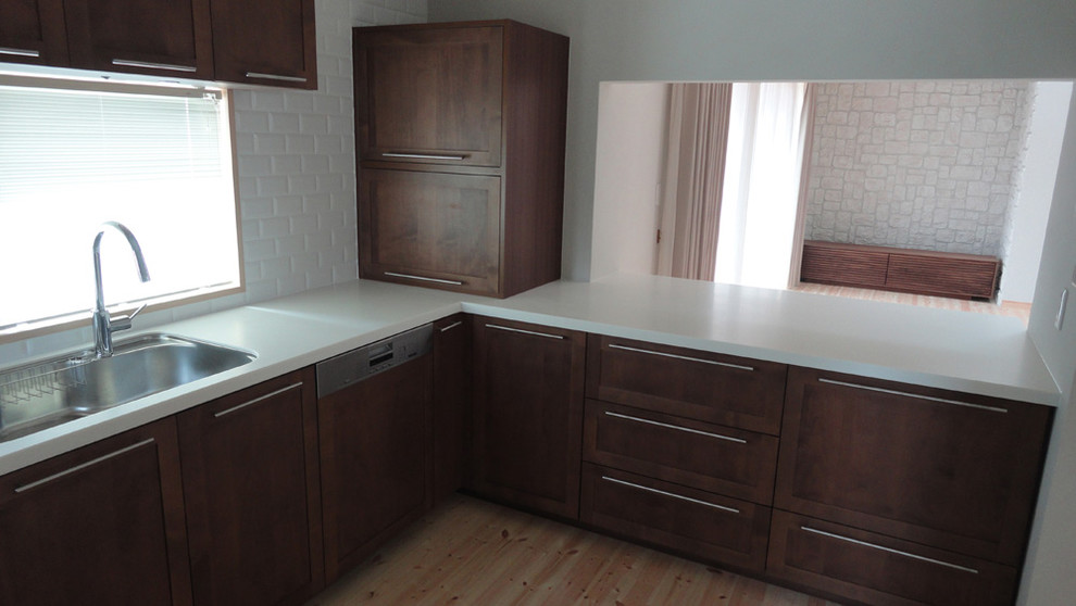 Photo of a scandinavian u-shaped kitchen in Other with an undermount sink, recessed-panel cabinets, white cabinets, solid surface benchtops and white benchtop.