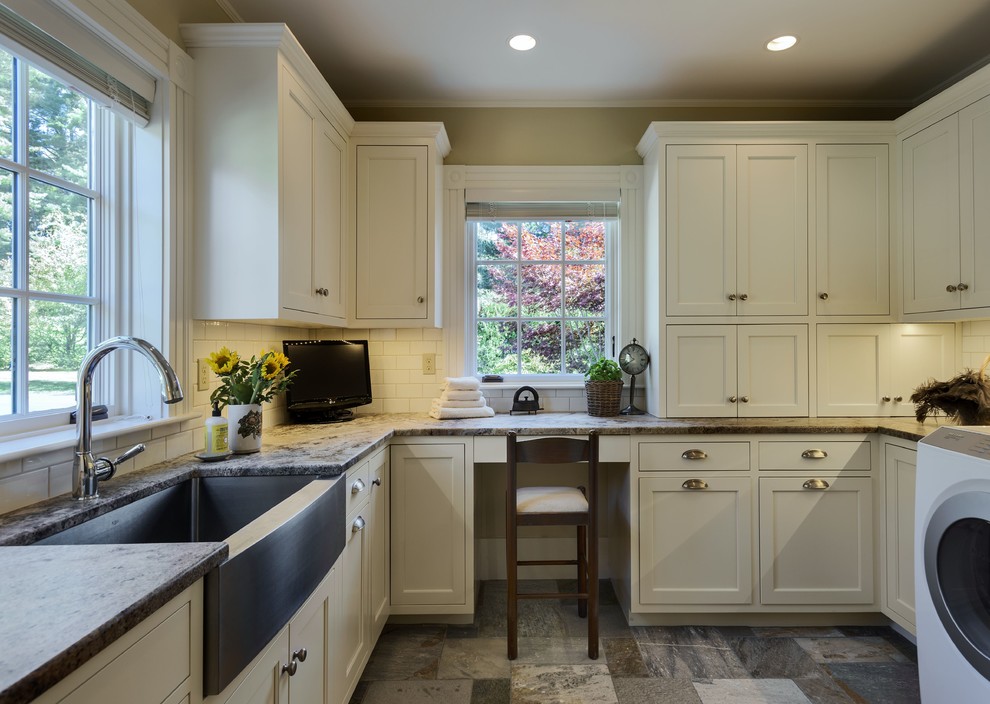 Inspiration for a transitional dedicated laundry room in Portland Maine with a farmhouse sink, white cabinets, recessed-panel cabinets, beige walls, granite benchtops, a side-by-side washer and dryer and travertine floors.