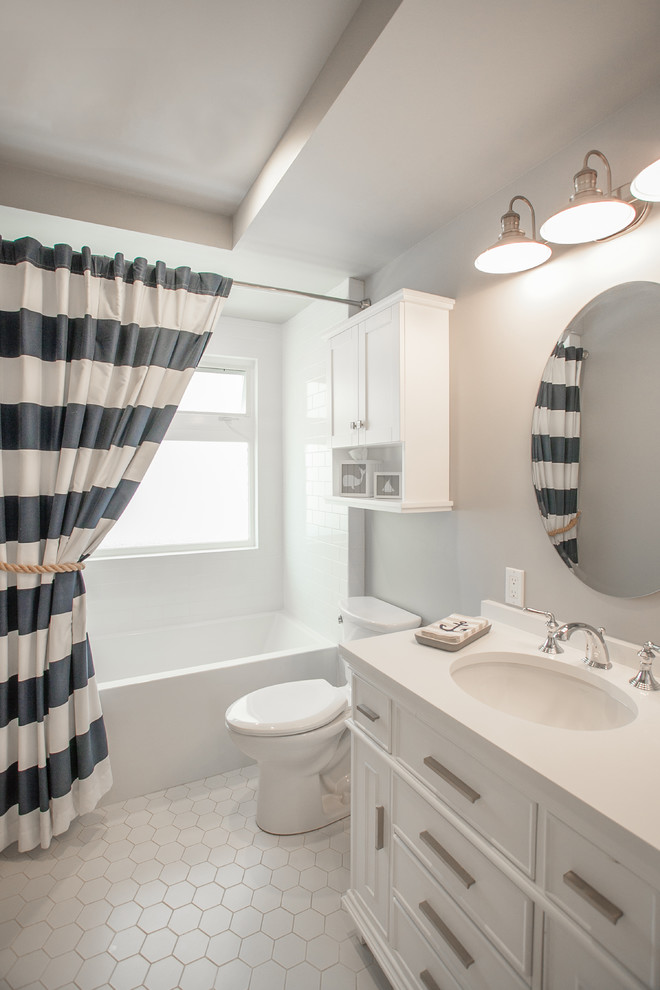Beach style master bathroom with recessed-panel cabinets, white cabinets, an alcove tub, a shower/bathtub combo, a wall-mount toilet, white tile, subway tile, white walls, porcelain floors, an undermount sink, laminate benchtops, white floor, a shower curtain and white benchtops.