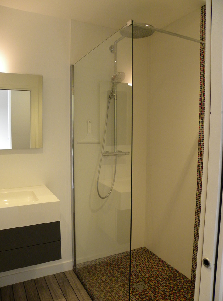 This is an example of a small contemporary 3/4 bathroom in Nantes with a curbless shower, mosaic tile, white walls, medium hardwood floors and a wall-mount sink.