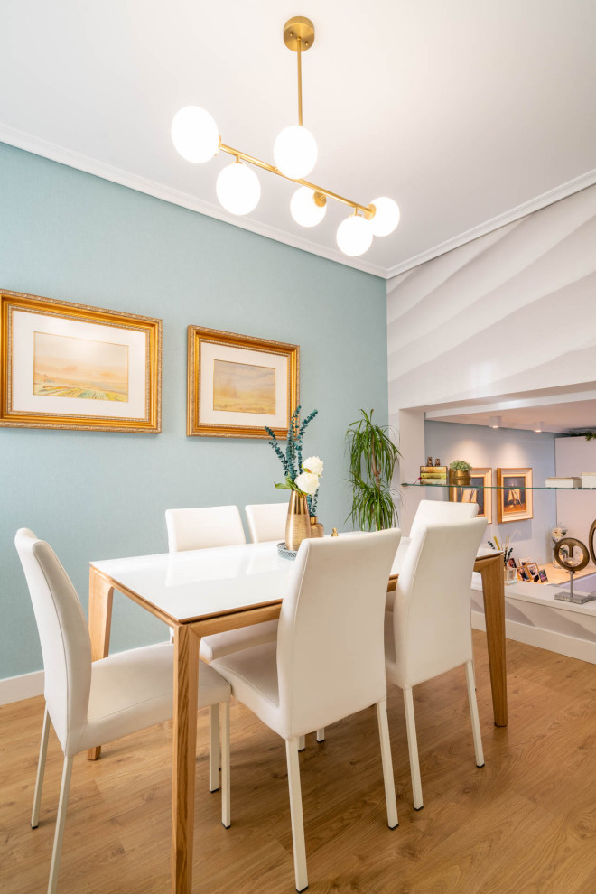 Свежая идея для дизайна: гостиная-столовая среднего размера в стиле неоклассика (современная классика) с синими стенами, полом из ламината, стандартным камином, фасадом камина из дерева, коричневым полом и обоями на стенах - отличное фото интерьера