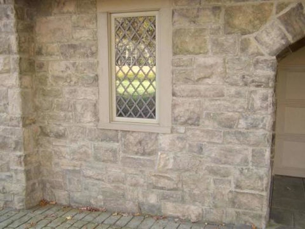 This is an example of a mid-sized country two-storey grey exterior in Richmond with stone veneer.