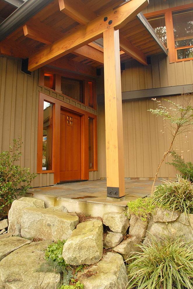 This is an example of a mid-sized arts and crafts front door in Vancouver with beige walls, ceramic floors and a medium wood front door.