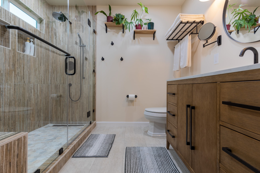 Cette image montre une salle de bain minimaliste de taille moyenne avec des portes de placard marrons, des carreaux de céramique, un plan de toilette en quartz modifié, un plan de toilette blanc, meuble simple vasque, WC à poser, un sol en carrelage de céramique, un lavabo encastré, une cabine de douche à porte battante, un banc de douche, un mur en parement de brique, un carrelage multicolore, un mur blanc, meuble-lavabo sur pied, un placard à porte plane et un sol beige.