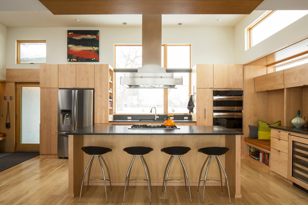 Contemporary kitchen in Minneapolis with an undermount sink, flat-panel cabinets, light wood cabinets, granite benchtops, stainless steel appliances, light hardwood floors and with island.