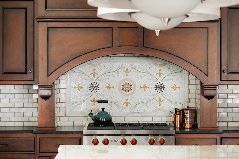 Klassisk inredning av ett mellanstort vit vitt kök, med luckor med profilerade fronter, grå skåp, marmorbänkskiva, vitt stänkskydd, stänkskydd i tunnelbanekakel, mellanmörkt trägolv, en köksö och brunt golv