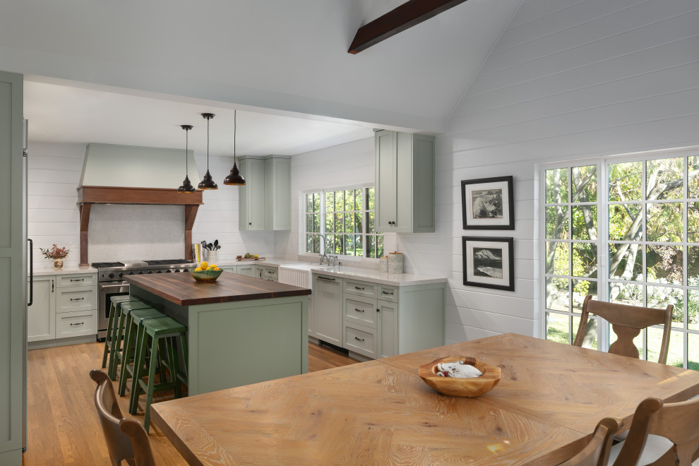 Inspiration for a large transitional u-shaped eat-in kitchen in Los Angeles with a farmhouse sink, recessed-panel cabinets, green cabinets, quartz benchtops, white splashback, shiplap splashback, panelled appliances, medium hardwood floors, with island, brown floor and white benchtop.