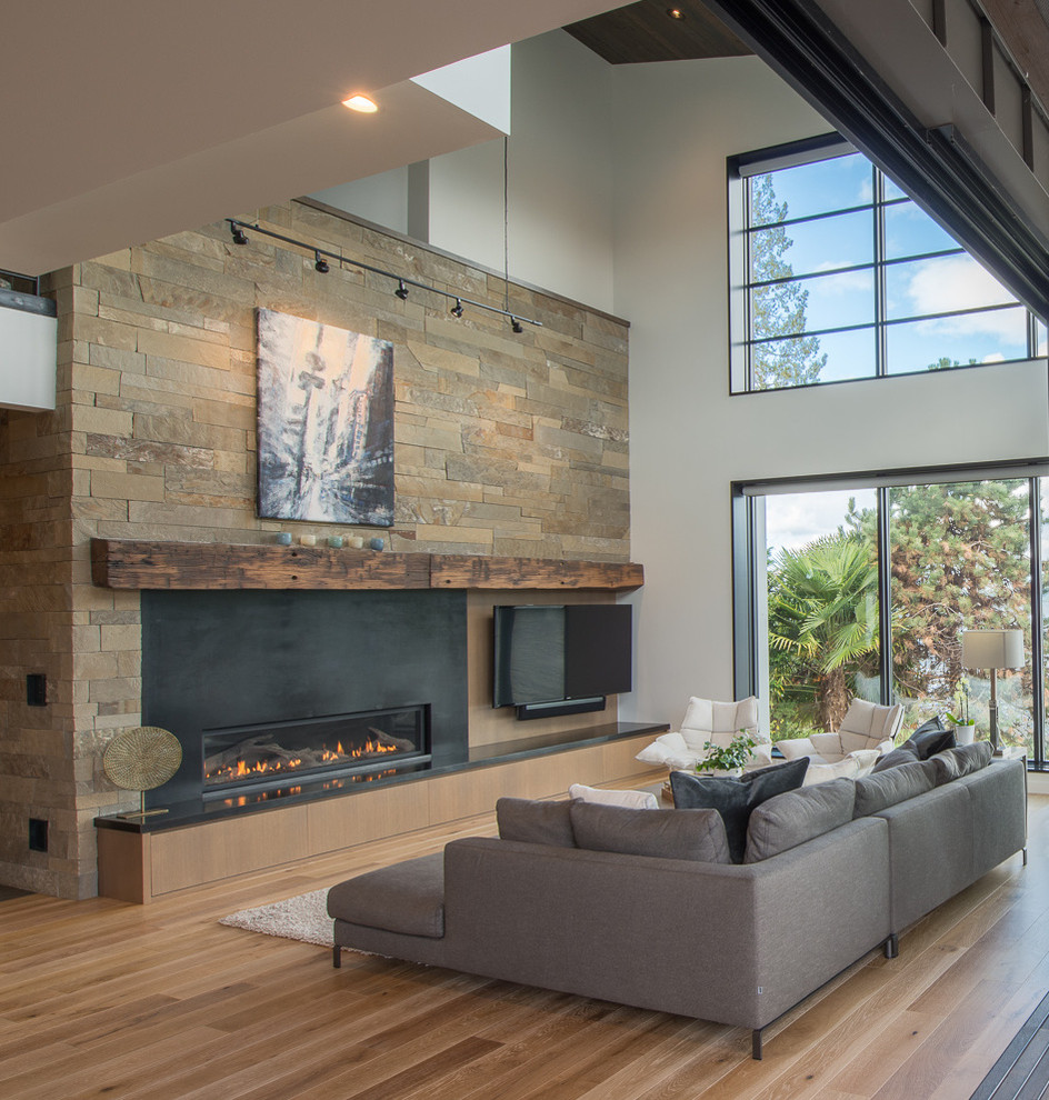 Large contemporary open concept living room in Seattle with white walls, medium hardwood floors, a ribbon fireplace, a wall-mounted tv, brown floor and a metal fireplace surround.