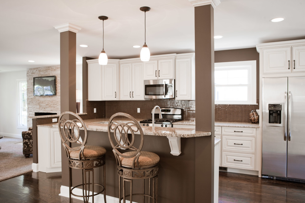 Kitchen - mid-sized transitional galley dark wood floor kitchen idea in St Louis with raised-panel cabinets, white cabinets, granite countertops, brown backsplash, mosaic tile backsplash, stainless steel appliances and an island