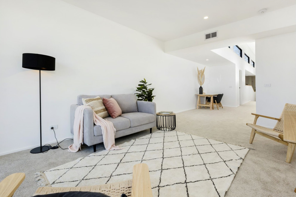 Large modern enclosed living room in Melbourne with white walls, light hardwood floors, no fireplace, no tv and grey floor.