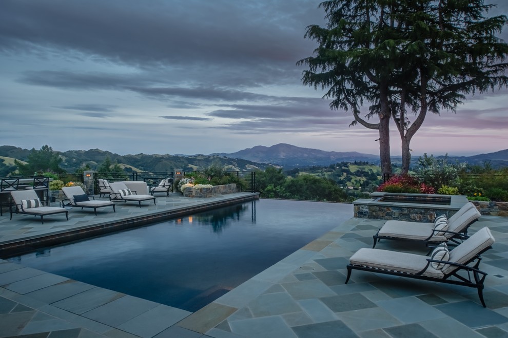 Photo of an expansive transitional backyard rectangular infinity pool in San Francisco with a hot tub and natural stone pavers.