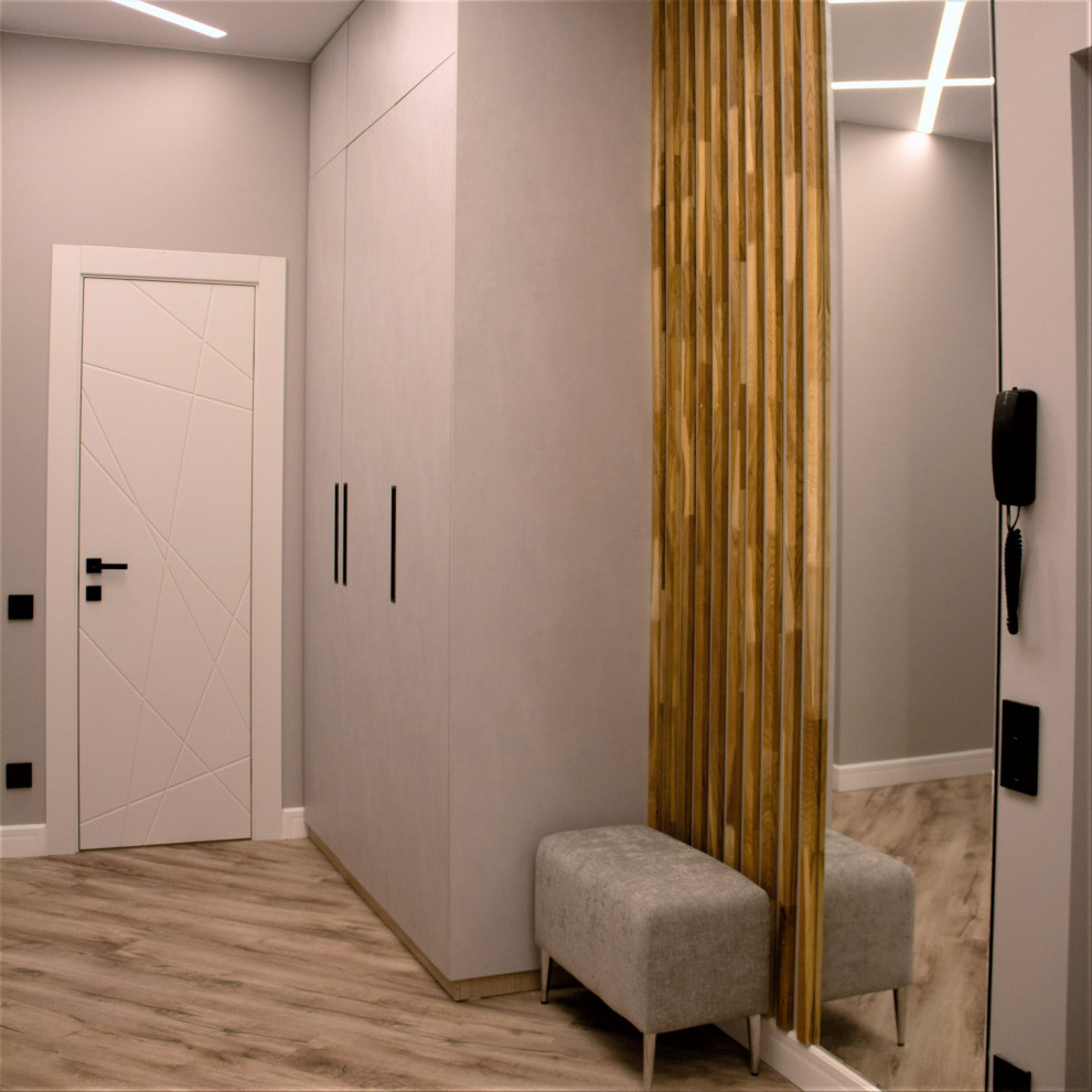 Idées déco pour une entrée contemporaine de taille moyenne avec un couloir, un mur gris, un sol marron et boiseries.