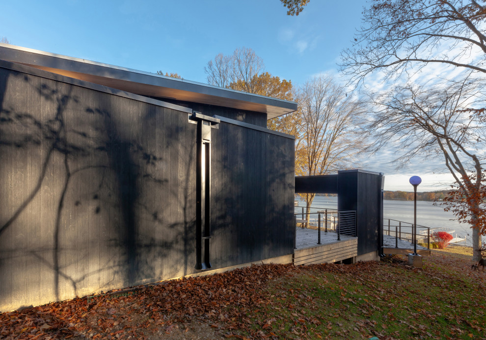 Ejemplo de fachada de casa negra moderna de tamaño medio de dos plantas con revestimiento de madera, tejado de un solo tendido y tejado de metal