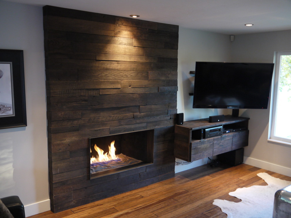 Photo of a mid-sized country open concept living room in Salt Lake City with white walls, bamboo floors, a standard fireplace, a wood fireplace surround and a wall-mounted tv.