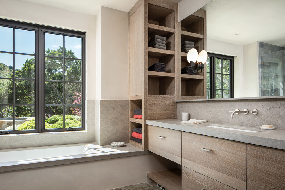 Inspiration for a large mediterranean master bathroom in Orange County with beige cabinets, a drop-in tub, an open shower, green tile, stone tile, beige walls, light hardwood floors, a drop-in sink, soapstone benchtops, beige floor, a hinged shower door and grey benchtops.