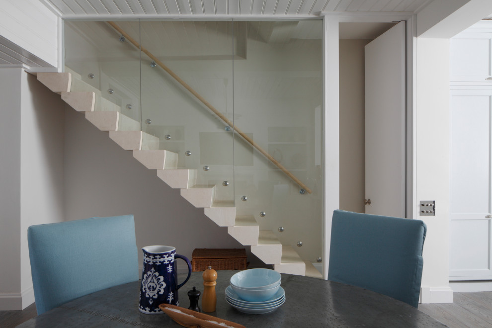 Пример оригинального дизайна: прямая лестница в современном стиле с ступенями из известняка, подступенками из известняка и стеклянными перилами
