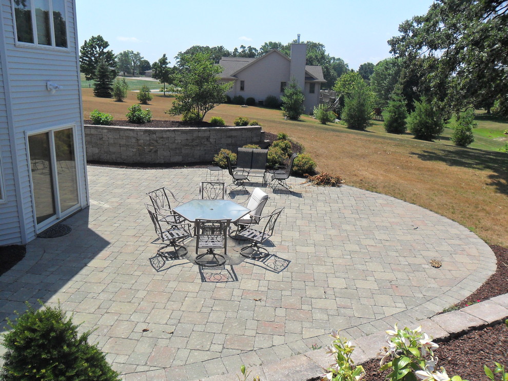 Mid-sized traditional backyard full sun garden in Milwaukee with a retaining wall and natural stone pavers.