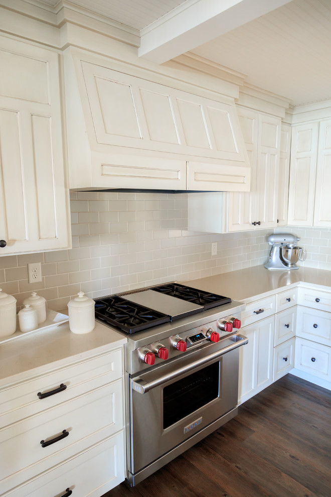 Inspiration for a transitional l-shaped vinyl floor open concept kitchen remodel in Minneapolis with an undermount sink, raised-panel cabinets, white cabinets, quartz countertops, beige backsplash, ceramic backsplash, paneled appliances and an island