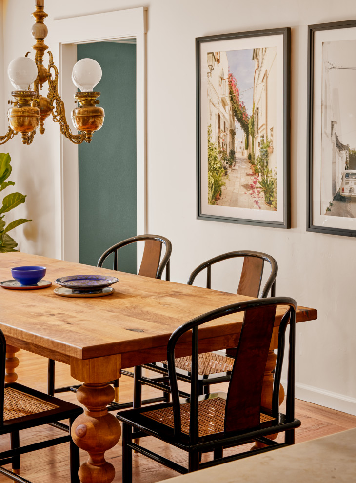 Cette photo montre une petite salle à manger ouverte sur la cuisine méditerranéenne avec un mur blanc, sol en stratifié et un sol marron.