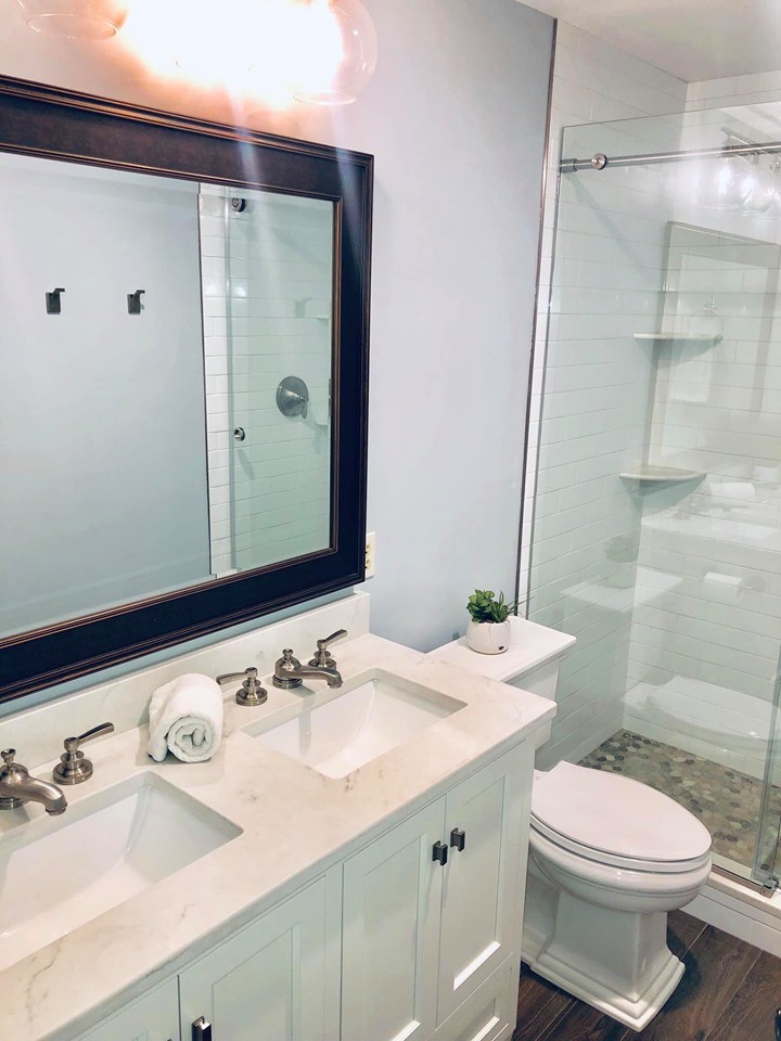 Photo of a mid-sized arts and crafts kids bathroom in Philadelphia with shaker cabinets, white cabinets, a corner shower, a two-piece toilet, white tile, porcelain tile, blue walls, porcelain floors, an undermount sink, marble benchtops, brown floor, a sliding shower screen and multi-coloured benchtops.