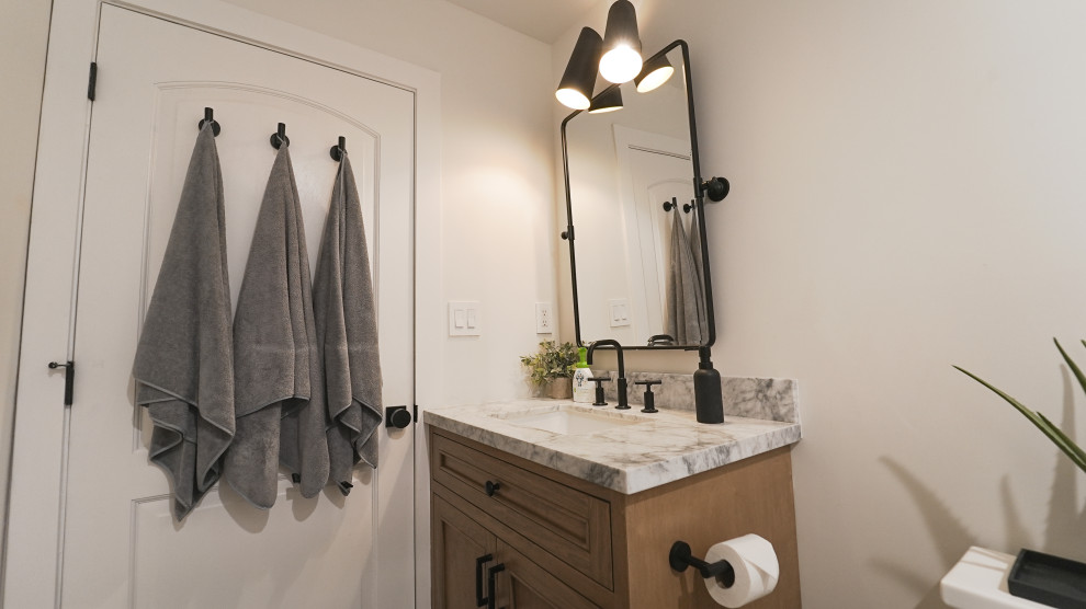 Mid-sized scandinavian kids bathroom in Los Angeles with shaker cabinets, medium wood cabinets, an alcove tub, an alcove shower, a one-piece toilet, white tile, ceramic tile, white walls, porcelain floors, an undermount sink, marble benchtops, white floor, a hinged shower door, white benchtops, a niche, a single vanity, a freestanding vanity, vaulted and wallpaper.