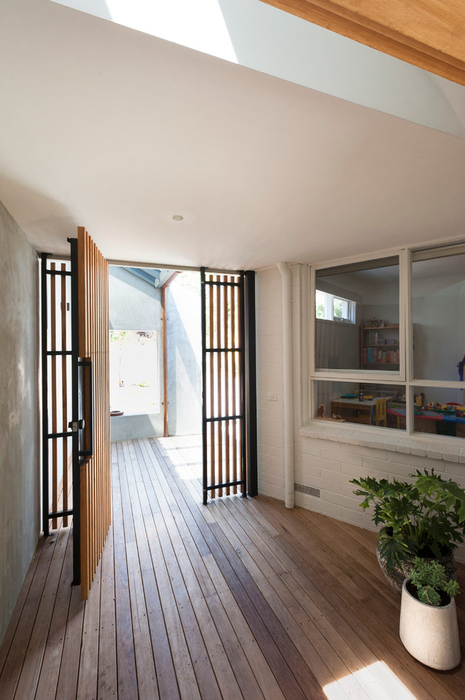 This is an example of a small contemporary front door in Melbourne with grey walls, light hardwood floors, a single front door and a light wood front door.