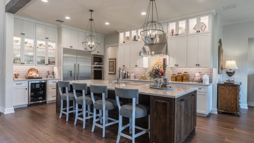 Inspiration for a transitional l-shaped dark wood floor and brown floor kitchen remodel in Austin with an undermount sink, shaker cabinets, white cabinets, gray backsplash, subway tile backsplash, an island and gray countertops