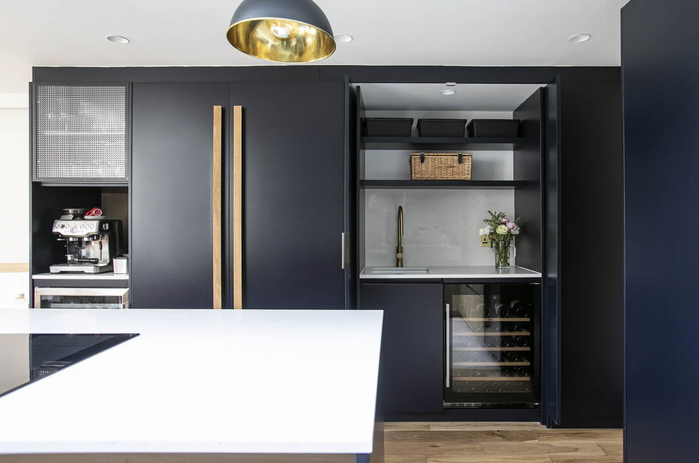 Photo of a small contemporary l-shaped open plan kitchen in London with a submerged sink, beaded cabinets, black cabinets, quartz worktops, white splashback, ceramic splashback, black appliances, ceramic flooring, an island, multi-coloured floors, white worktops, a vaulted ceiling and feature lighting.