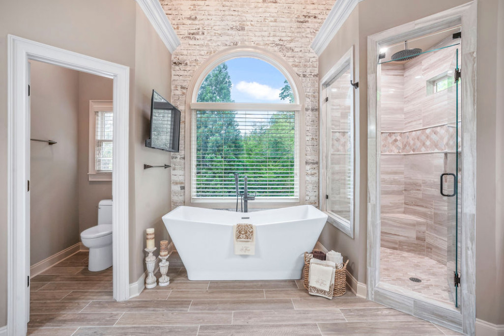 This is an example of a large traditional master bathroom in Atlanta with furniture-like cabinets, white cabinets, a freestanding tub, a corner shower, a one-piece toilet, gray tile, ceramic tile, beige walls, ceramic floors, an undermount sink, granite benchtops, beige floor, a hinged shower door, white benchtops, a shower seat, a single vanity, a freestanding vanity, vaulted and brick walls.