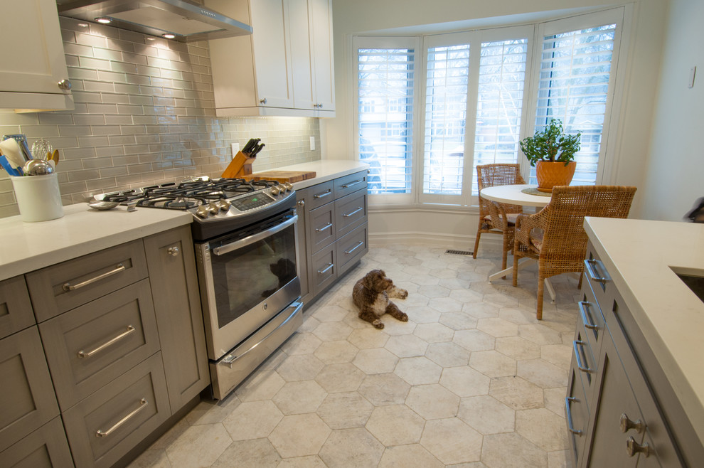Example of a mid-sized transitional galley ceramic tile enclosed kitchen design in Toronto with shaker cabinets, white cabinets, quartzite countertops, gray backsplash, glass tile backsplash, stainless steel appliances and no island