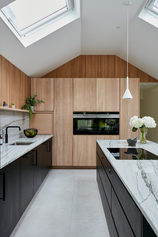 Photo of a large scandinavian open plan kitchen in London with a built-in sink, flat-panel cabinets, black cabinets, quartz worktops, multi-coloured splashback, black appliances, an island and multicoloured worktops.