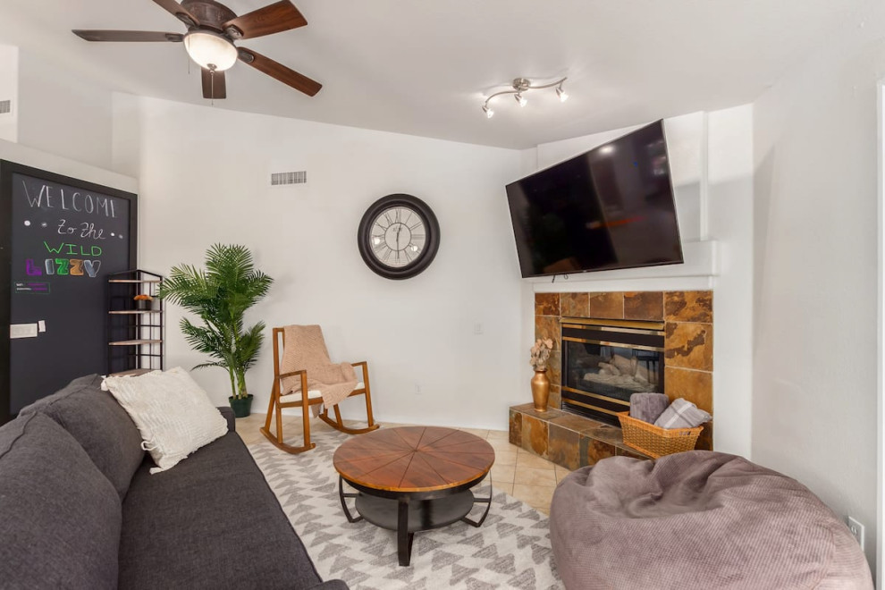 フェニックスにあるお手頃価格の中くらいなミッドセンチュリースタイルのおしゃれなLDK (白い壁、セラミックタイルの床、コーナー設置型暖炉、タイルの暖炉まわり、壁掛け型テレビ、ベージュの床、三角天井) の写真