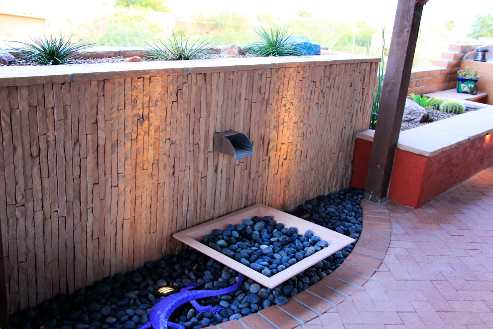 Photo of a mid-sized backyard patio in Phoenix with a water feature, brick pavers and a roof extension.
