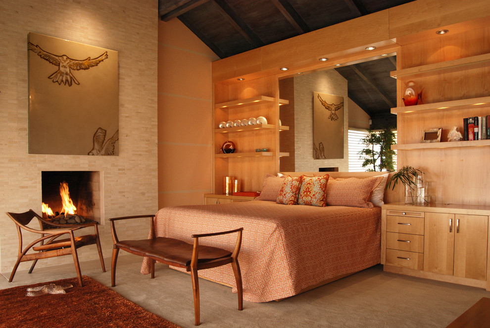 Immagine di una camera da letto stile marino con pareti beige, moquette, camino classico e cornice del camino piastrellata