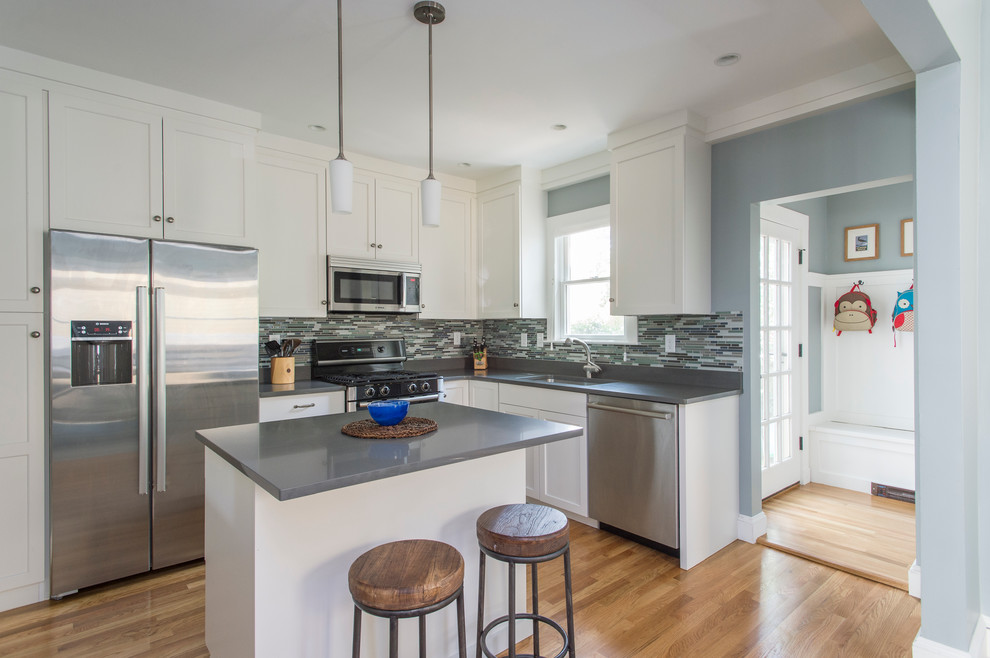 Mid-sized transitional l-shaped medium tone wood floor open concept kitchen photo in Boston with a single-bowl sink, shaker cabinets, white cabinets, quartz countertops, multicolored backsplash, matchstick tile backsplash, stainless steel appliances and an island